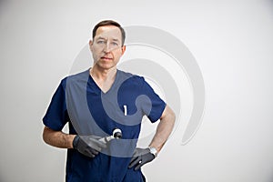 portrait of a male cosmetologist doctor in a blue medical uniform and black gloves with a dermatoscope in his hands.