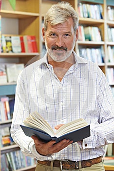 Portrait Of Male Customer Reading Book In Bookstore