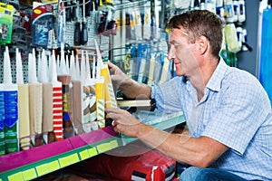 Portrait of male customer selecting sealant bottle i