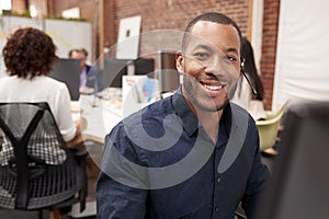 Portrait Of Male Customer Services Agent Working At Desk In Call Center