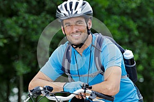 Portrait male cyclist leaning on handlebars