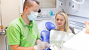 Portrait of male dentist writing prescription to his woman patient