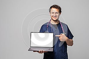 Portrait Of Male Doctor Showing Laptop Over White Background