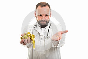 Portrait of male doctor showing measuring tape and pill