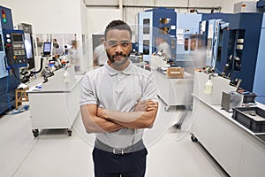 Portrait Of Male Engineer On Factory Floor Of Busy Workshop