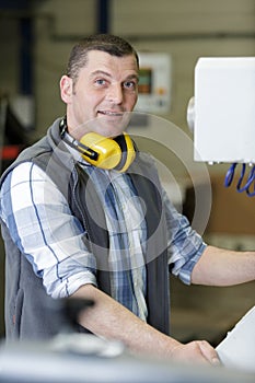 Portrait male engineer operating cnc machinery in factory