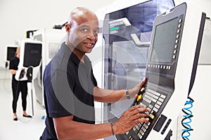 Portrait Of Male Engineer Operating CNC Machinery In Factory