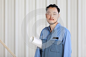 Portrait of male engineer with self-confidense and friendly manner, holding roll paper in hand