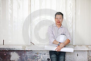 Portrait of male engineer with self-confidense and friendly manner, holding roll paper in hand