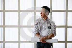 Portrait of male engineer with self-confidense and friendly manner, holding roll paper in hand