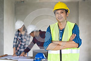 Portrait male engineer wearing safety helmet and holding blueprint in construction site