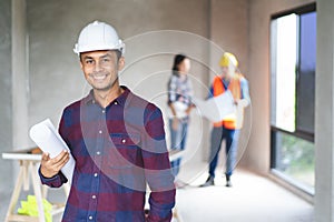 Portrait male engineer wearing safety helmet and holding blueprint in construction site