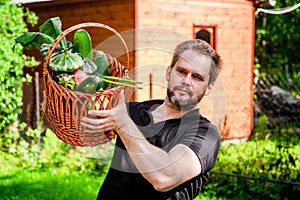 Portrait of a male farmer holding a basket of vegetables.Harvest of ecologically clean ripe vegetables and fruits