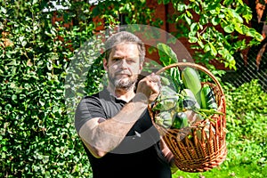 Portrait of a male farmer holding a basket of vegetables.Harvest of ecologically clean ripe vegetables and fruits