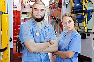Portrait of male and female attentive paramedicals near ambulance car