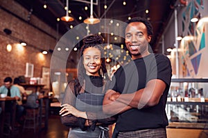 Portrait Of Male And Female Coffee Shop Owners Standing At Sales Desk