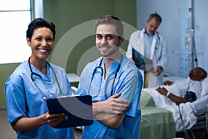 Portrait of male and female nurse standing in ward