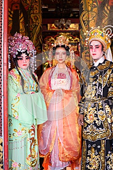 Portrait of male and female opera performers at the entrance to a sacred shrine or temple, praying for blessings on the occasion
