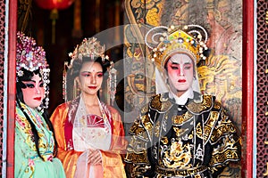 Portrait of male and female opera performers at the entrance to a sacred shrine or temple, praying for blessings on the occasion