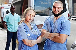 Portrait of male and female paramedicals near ambulance car0