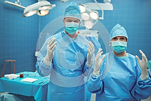 Portrait of male and female surgeon standing in operation theater