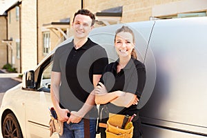 Portrait of male and female trade workers by a van