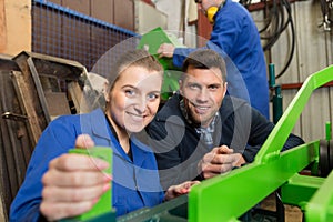 portrait male and female workers by industrial machine