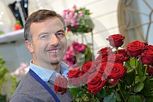 portrait male florist holding bunch red roses