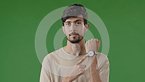 Portrait of male frustrated indian hispanic guy young man standing over green background waiting for meeting angry