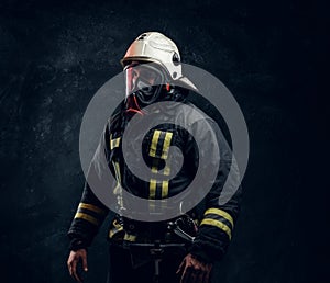 Portrait of a male in full firefighter equipment posing in a dark studio