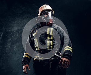 Portrait of a male in full firefighter equipment posing in a dark studio