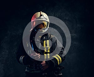 Portrait of a male in full firefighter equipment posing in a dark studio
