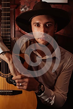 portrait of a male guitarist sitting with a guitar