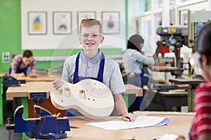 Portrait Of Male High School Student Building Guitar In Woodwork