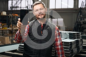 Portrait of male holding smartphone in the workshop