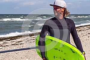 Portrait of a male kite foil surfer with a board on the beach