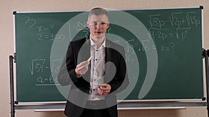 Portrait of a male math teacher in college near the blackboard.