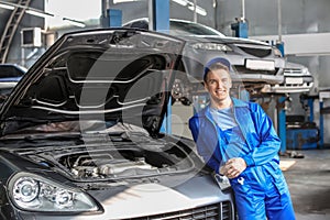 Portrait of male mechanic near car in service center