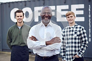 Portrait Of Male Multi-Cultural Freight Haulage Team Standing By Shipping Container