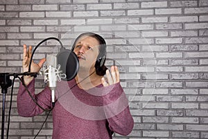 Portrait of male musician who sings song into microphone. Studio shot.