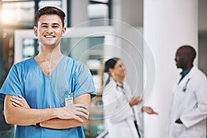 Portrait of a male nurse with his team in the background in the hospital. Happy, smiling and confident nurse with