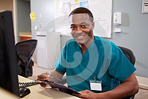 Portrait Of Male Nurse Working At Nurses Station