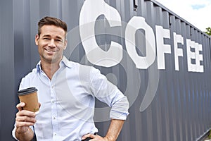 Portrait Of Male Owner Of Coffee Shop Or Distribution Business Standing By Shipping Container