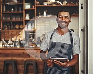 Portrait of a male owner holding digital tablet in his cafe