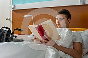 Portrait of male patient lying in the hospital bed and reading a