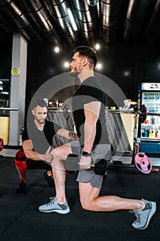 Portrait of male personal trainer working out and assisting clients in the gym. Fitness details