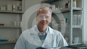 Portrait of a male pharmacist rotating on a chair and smiling at camera