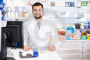 Portrait of male pharmacist working at the cash register in pharmacy