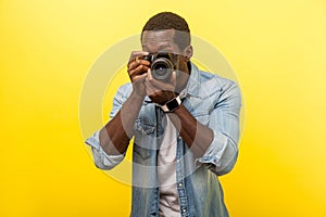 Portrait of male photographer or traveler in denim casual shirt holding professional digital dslr camera and focusing. isolated on