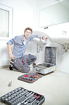 Portrait of male plumber fixing a sink in bathroom